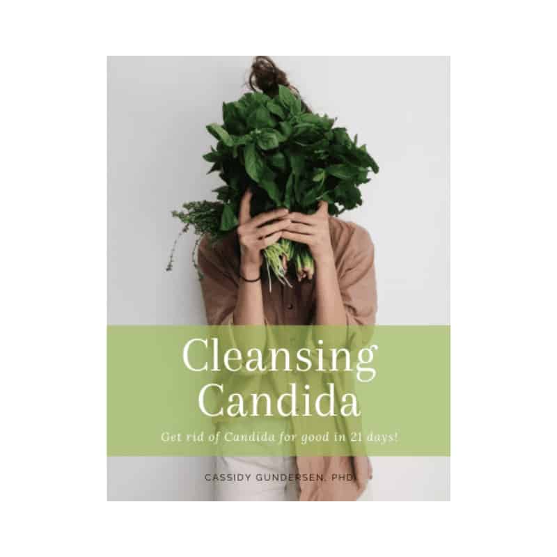 Woman holding a large bunch of fresh green herbs covering her face, promoting natural candida cleansing.