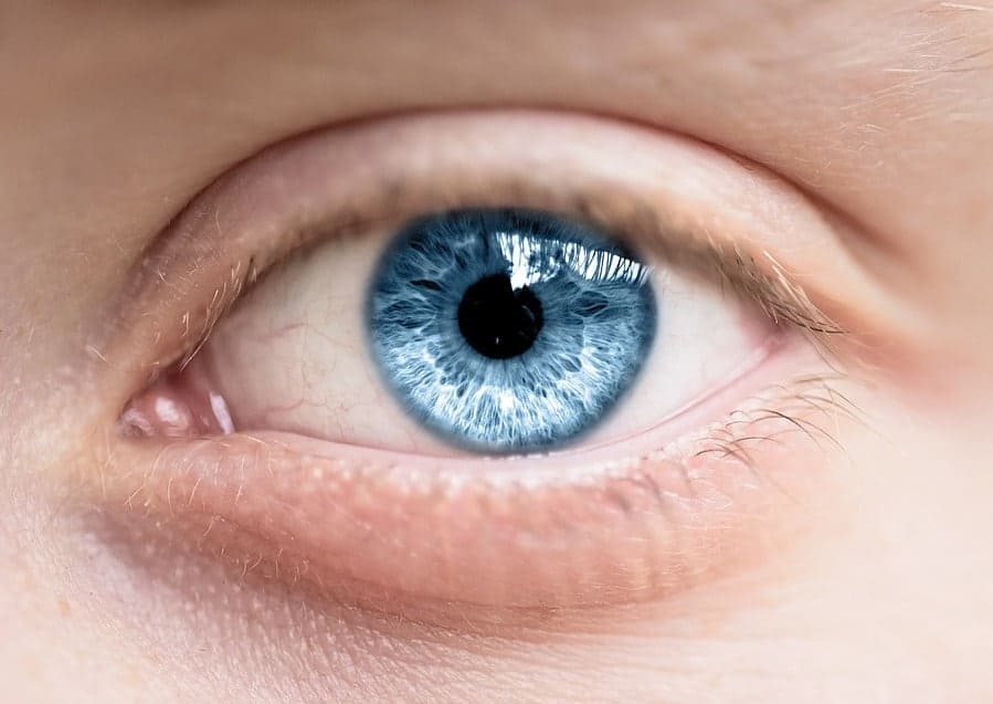 Up of a bright blue human eye with detailed iris and eyelashes.
